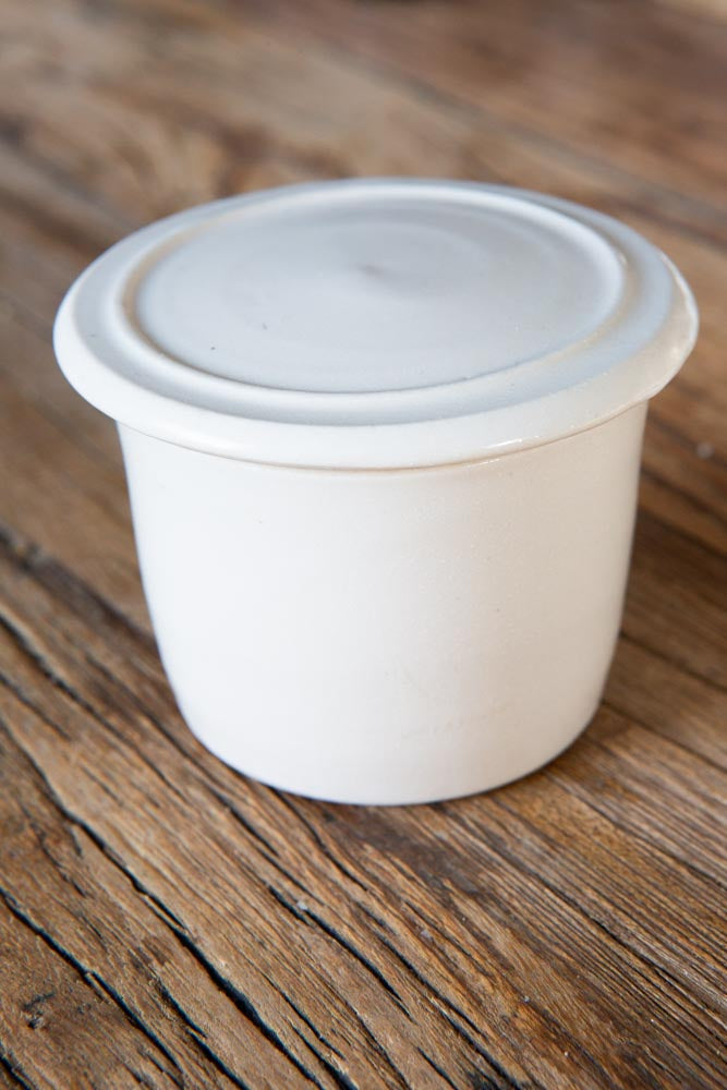 Ceramic condiment pot with lid, on a wood surface