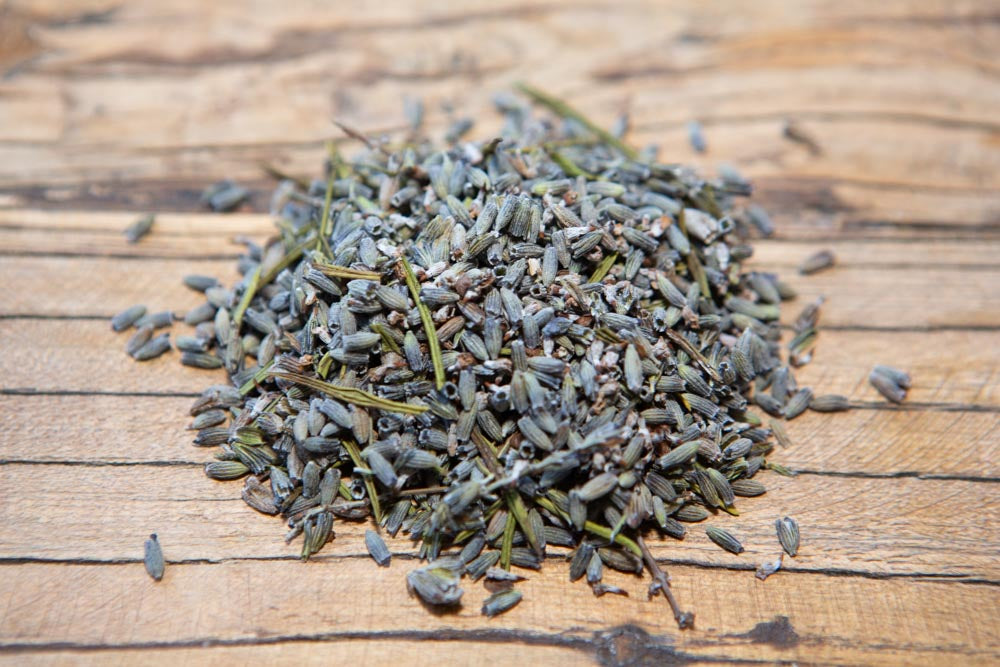 pile of dried lavender buds on a wooden surface