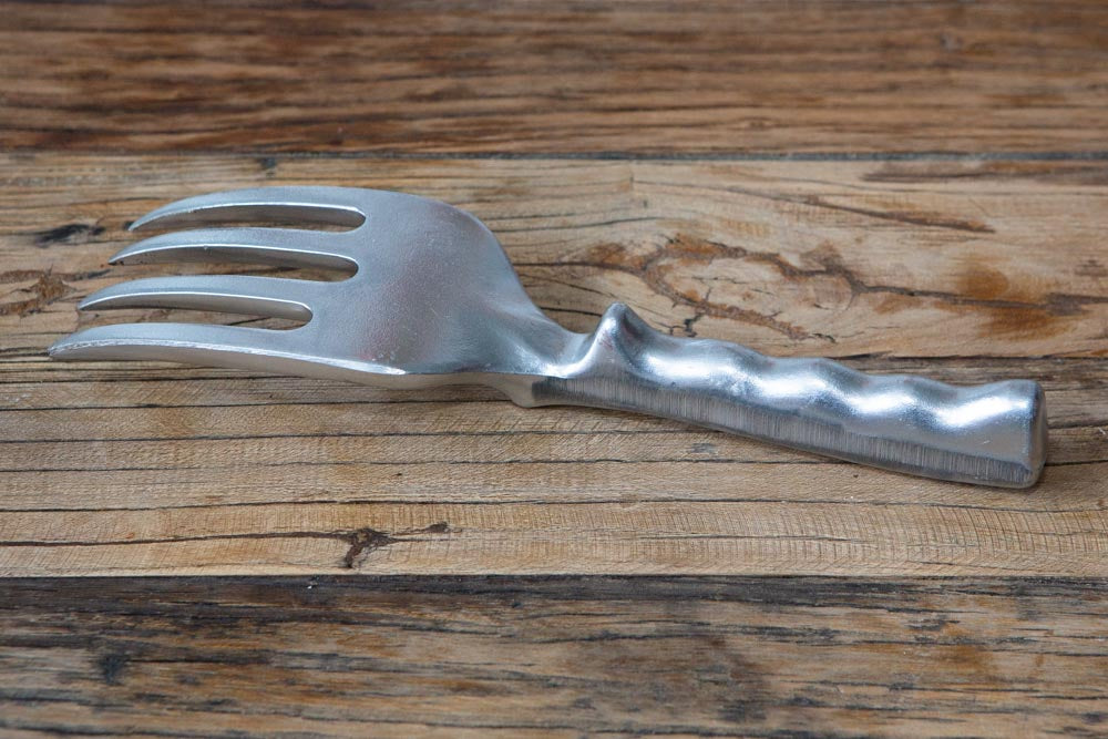 A metal garden fork faced down on a wooden surface