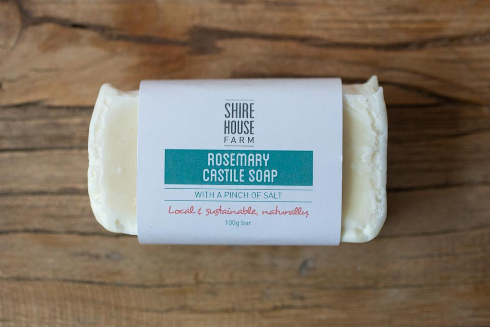 A bar of soap with a branded paper wrap around it, on a wooden surface