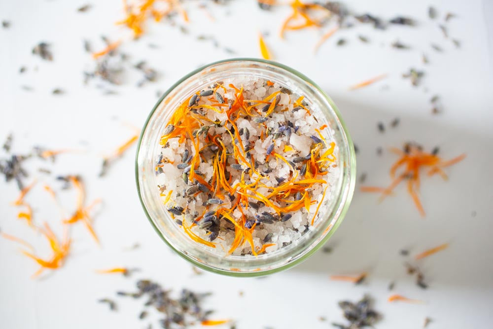 Flat lay photo of a glass jar with salt and flower petals