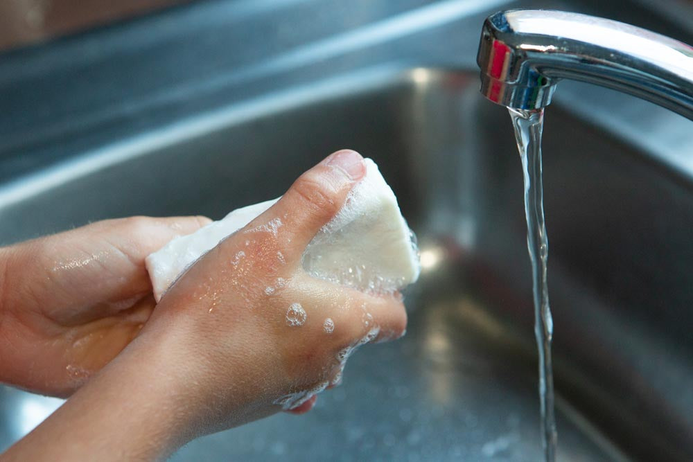 A child washing hands with soap and a running tap