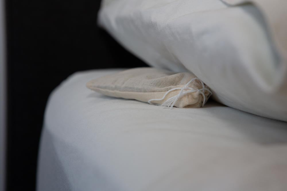 A pouch of lavender buds, lying between a mattress and a pillow