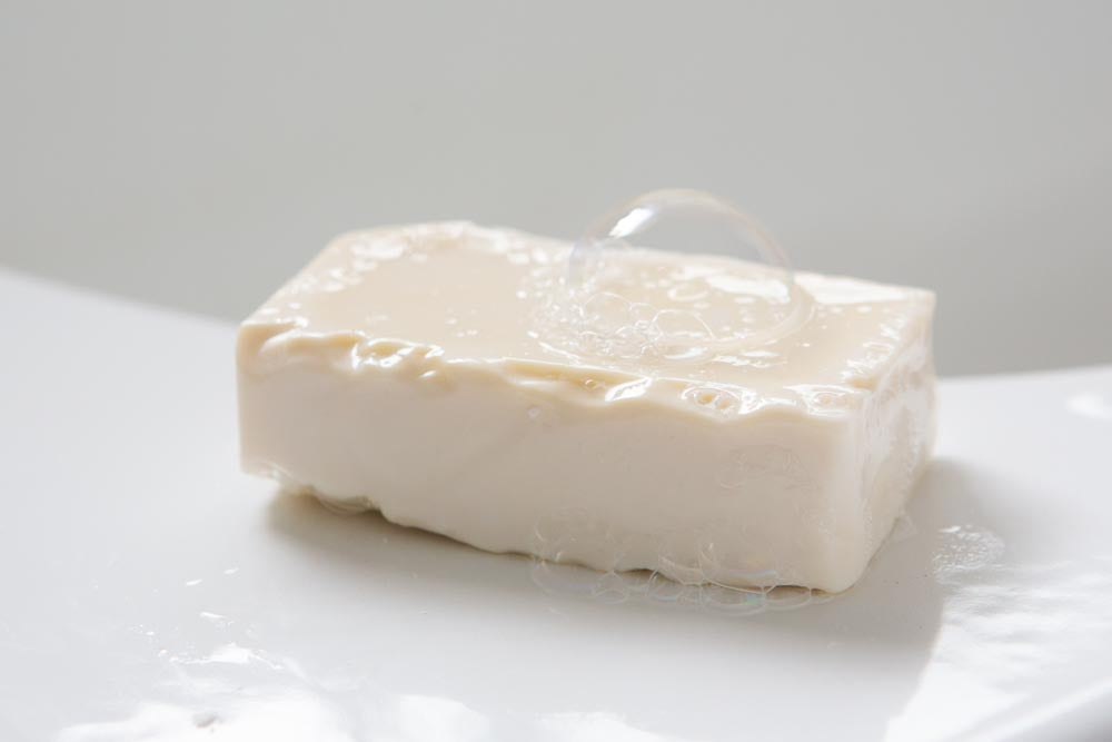A bar of wetted soap on the edge of a white bath
