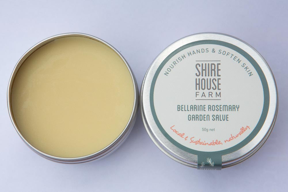 A tin of hand balm with the lid to the right side, on a white background