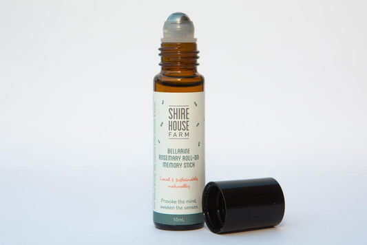A roll on bottle of rosemary essential oil, with the lid off, on a white background