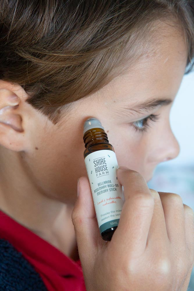 A child using a bottle of roll on essential oil on the temples of the head